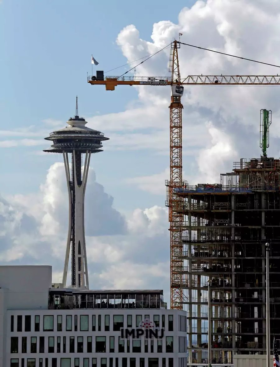 A tower crane and a building under construction beside the Space Needle in Seattle